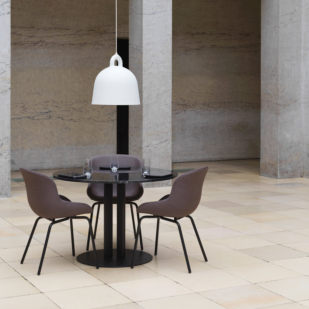 Modern black round dining table with elegant white pendant light and taupe upholstered chairs in a minimalist space.