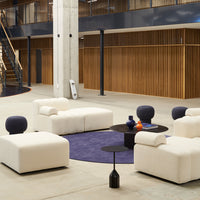 Modern beige furniture set on a rich purple rug, accented with black and colorful decor elements against wood tones.
