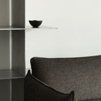 Textured black fabric sofa with subtle patterns, complemented by a minimalist black bowl on a sleek shelf.