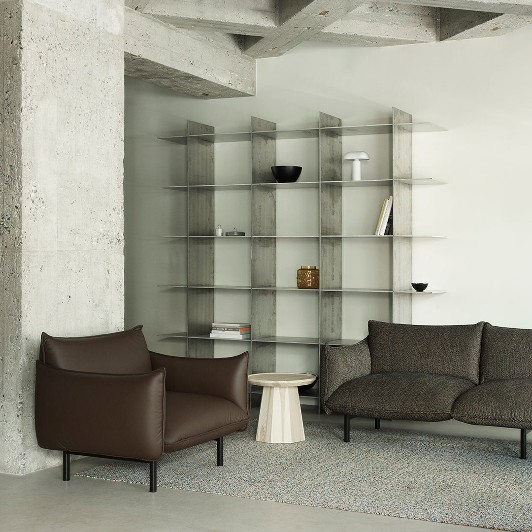 Brown leather armchair and dark gray fabric couch in a modern, minimalistic living room with a neutral color palette.