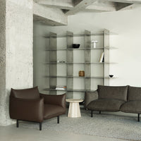 Brown leather armchair and dark gray fabric couch in a modern, minimalistic living room with a neutral color palette.