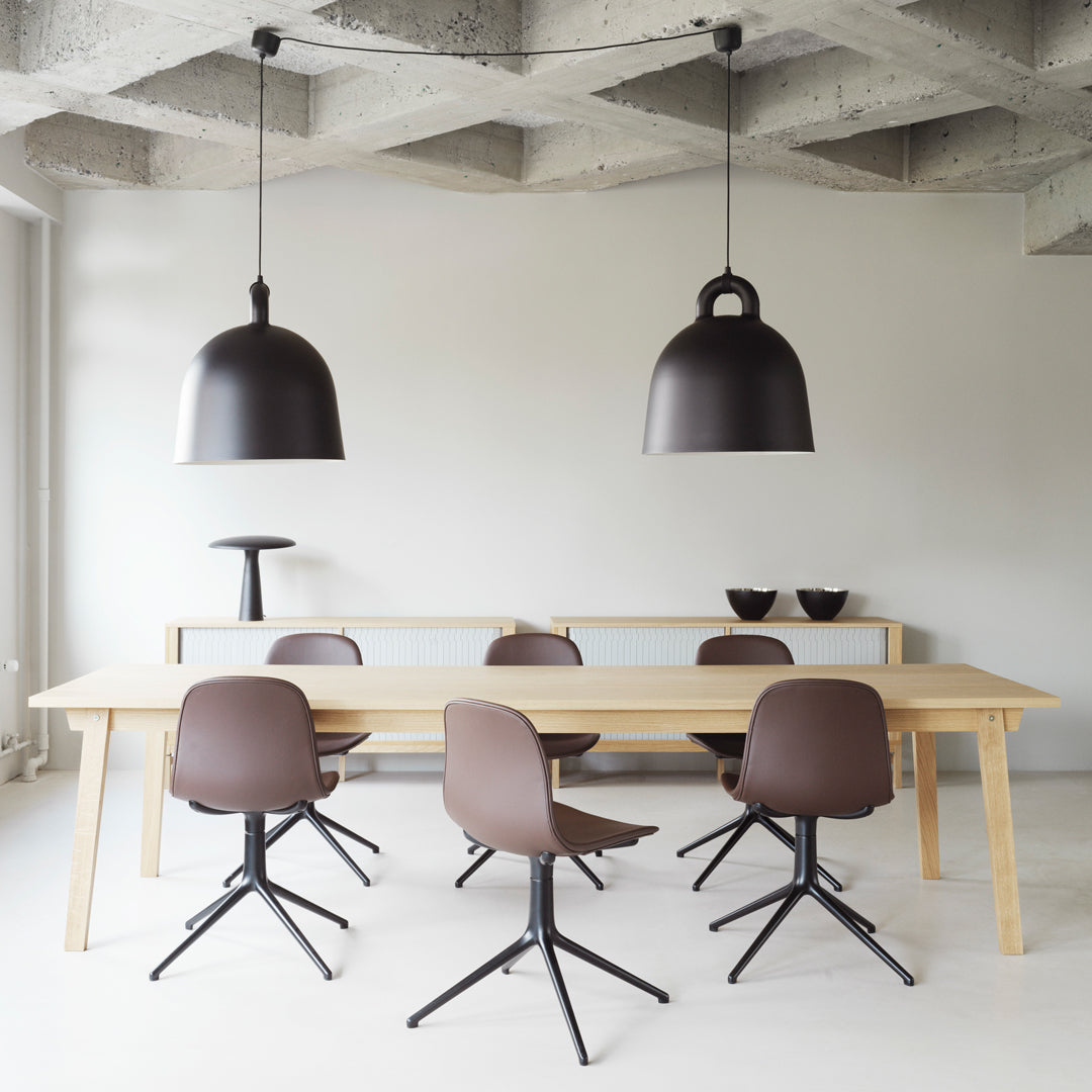 "Modern dining room featuring brown chairs, light wood table, and sleek black pendant lamps against a neutral backdrop."