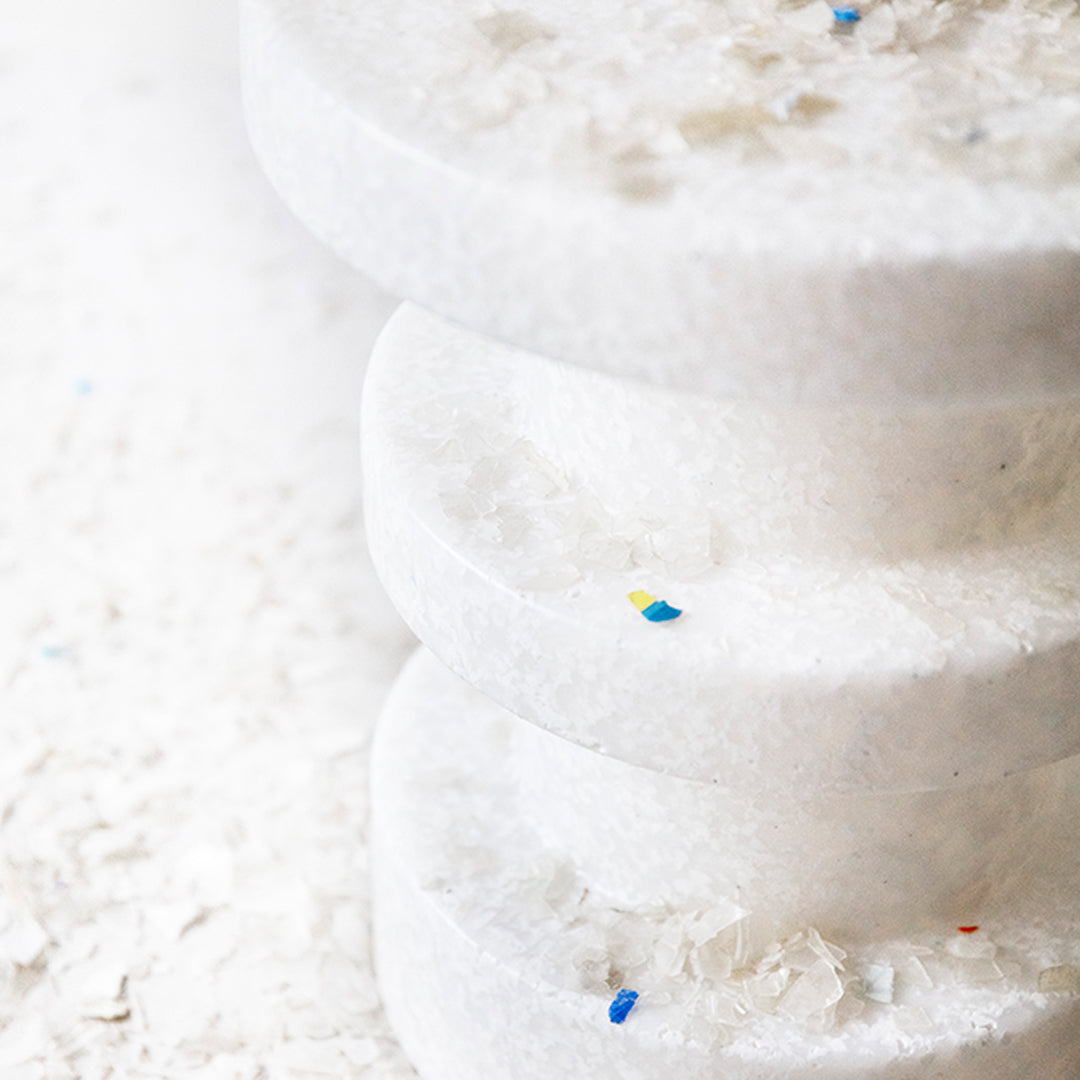 "Stacked white discs with colorful flecks on a soft white background, showcasing a minimalist and modern design."
