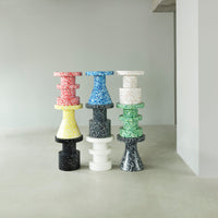 Colorful stack of patterned stools in red, blue, yellow, white, green, and black, showcasing modern design.