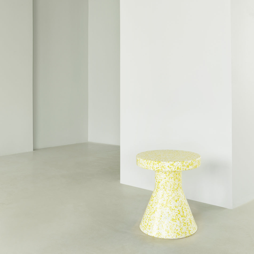Yellow speckled patterned side table in modern minimalist setting, perfect for adding a pop of color.