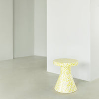 Yellow speckled patterned side table in modern minimalist setting, perfect for adding a pop of color.