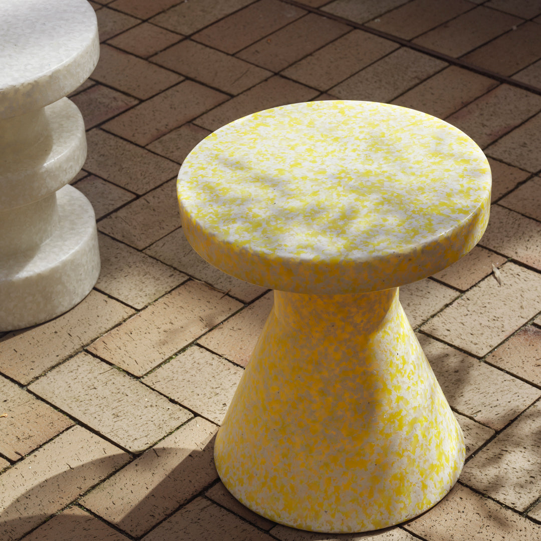 Yellow speckled accent table with a modern design, featuring a textured finish on a geometric shape.