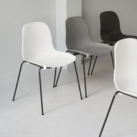 Modern chairs in white, gray, and black with sleek, minimalistic design and metal legs on a light gray floor.