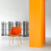 Bright orange chair against a vibrant orange wall, complemented by sleek gray shelving in a modern setting.