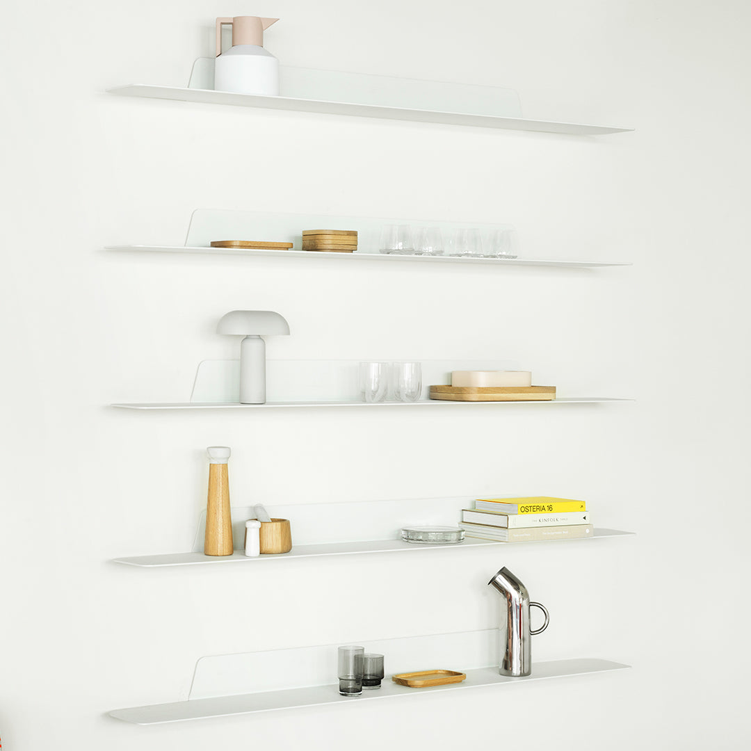 Modern white shelves displaying glassware, wooden decor, and sleek kitchen accessories in neutral tones with subtle patterns.