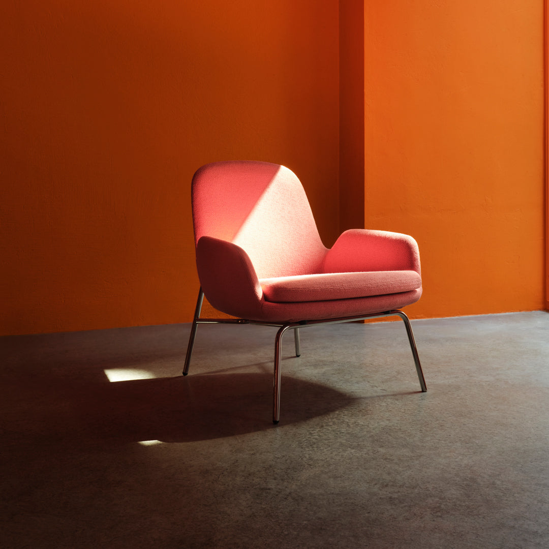 Modern pink chair against an orange wall, showcasing a sleek design and soft textures. Perfect for stylish interiors.