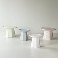 Set of four side tables in pastel green, blue, pink, and natural wood tones with geometric designs.