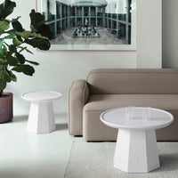 Modern geometric side tables in white with a minimalist design, paired with a neutral beige sofa and green plant.