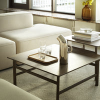 Modern coffee table with a sleek black finish, set against a soft beige sofa and neutral-toned carpet.