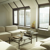 Modern beige sofa set with minimalist black coffee table and large windows, creating a light and airy atmosphere.