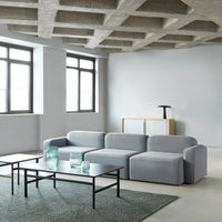 Light grey sectional sofa with a smooth fabric texture, paired with a dark metal coffee table and green rug for contrast.