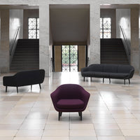 Modern seating collection featuring a deep purple chair and sleek black sofas against a light tiled floor.
