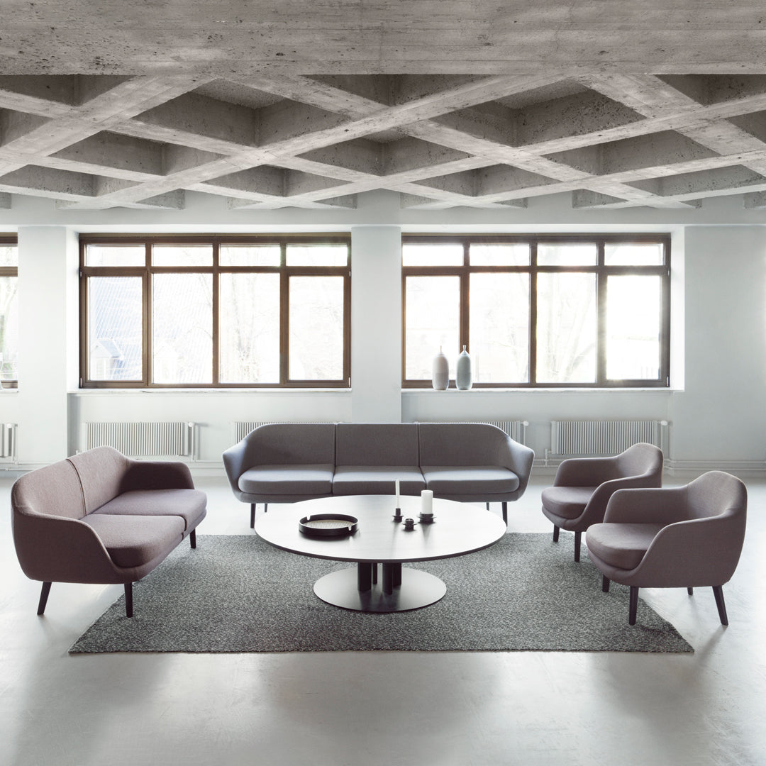 Modern living room featuring gray and light purple furniture with a circular black coffee table on a textured gray rug.