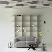 Gray textured sofa with a minimalist geometric pattern, set against a pale green wall and neutral decor elements.