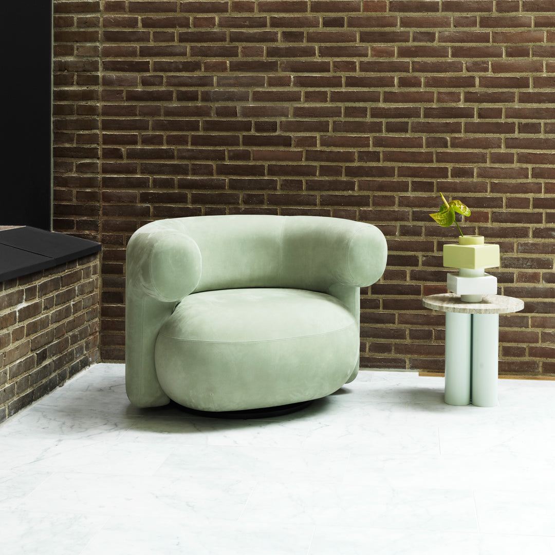 Soft mint green upholstered chair with rounded edges, complemented by a minimalist beige and green side table.