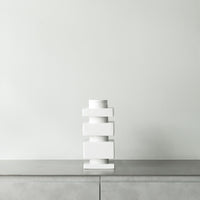 Modern white ceramic vase with stacked geometric shapes against a minimalist, light grey background.