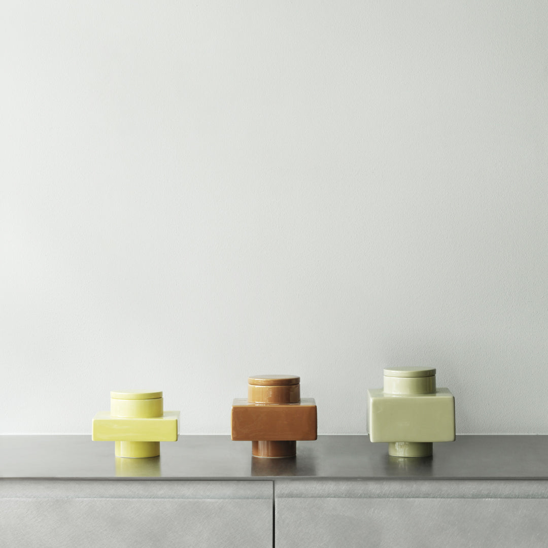 "Three geometric vases in yellow, brown, and pastel green against a minimalist background."