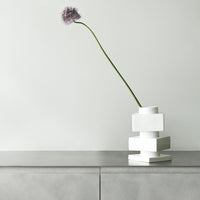 Modern white stacked vase with a minimalist design and smooth surface, featuring a single purple flower accent.