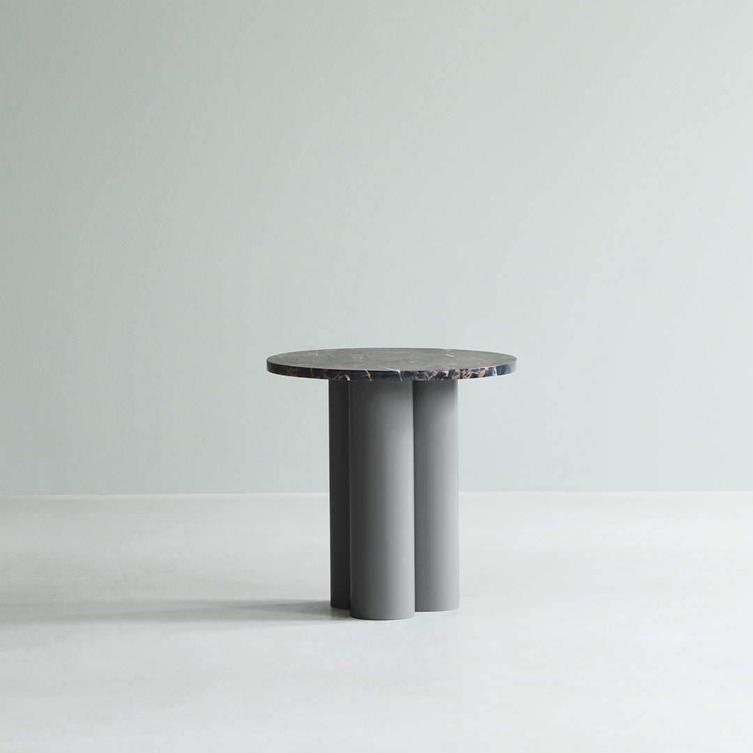 Round table with a speckled top in shades of gray and blue, featuring a minimalistic design with cylindrical legs.