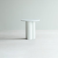 Modern round table in light gray with a smooth surface and cylindrical white legs, perfect for contemporary decor.