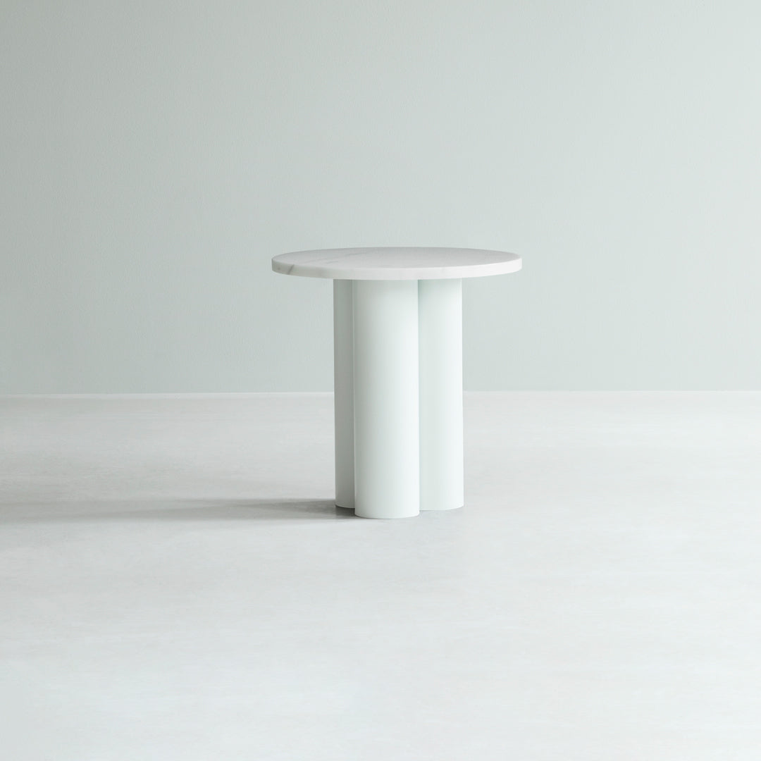 Round white table with a smooth surface and minimalist cylindrical base against a light gray background.
