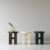 Set of three stylish wooden stools in dark brown, natural light wood, and deep green, showcasing minimalist design.