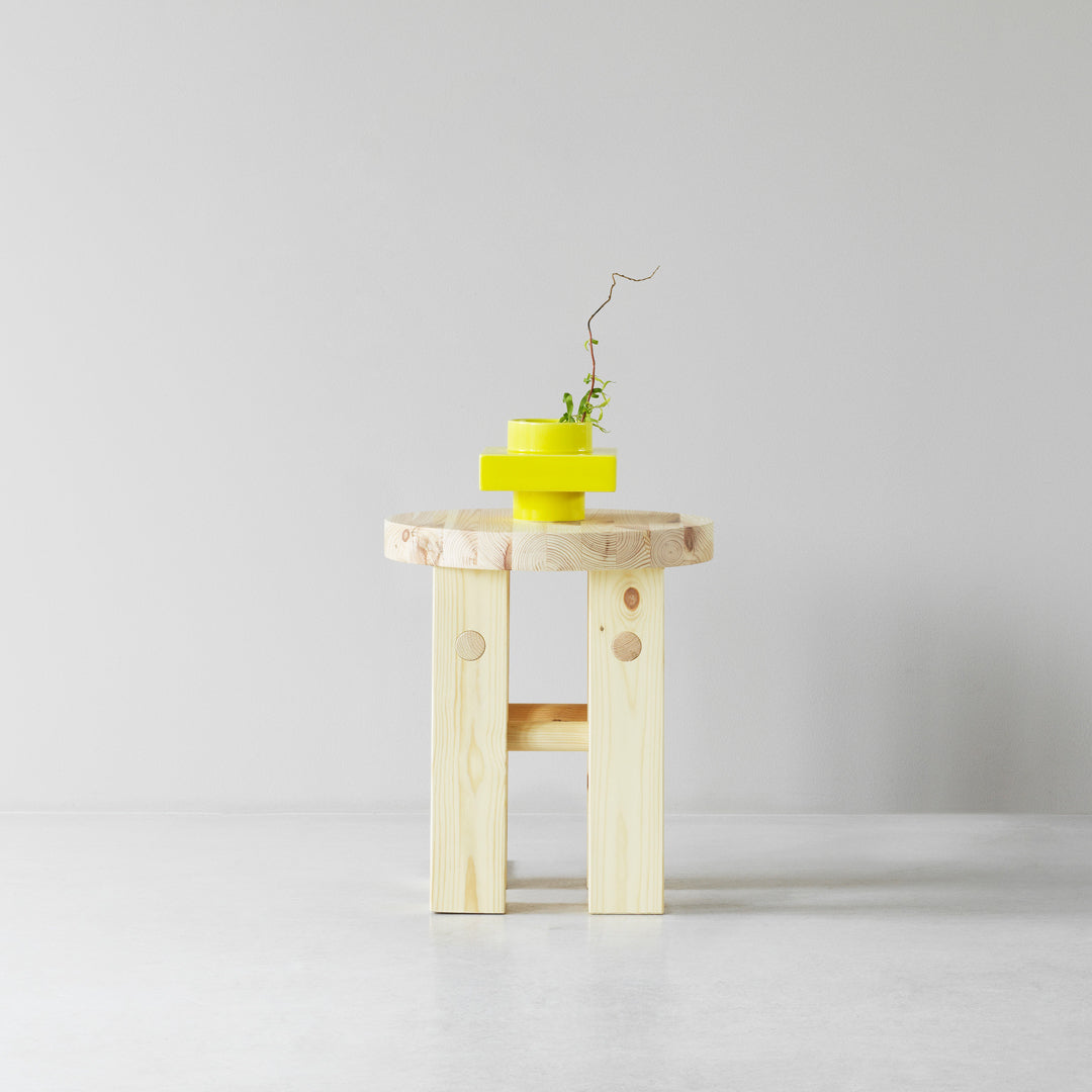 Natural wood table with light yellow accents and a green plant for a fresh, modern look.
