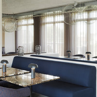 Stylish blue sofa with marble tabletop, featuring neutral curtains and modern lighting accents in a contemporary setting.