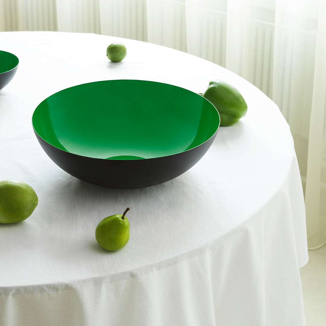 Black and green gradient bowl on a white tablecloth, surrounded by green apples. Perfect for modern decor.