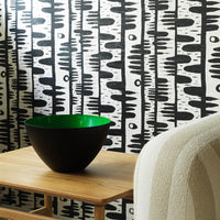 Black and white geometric wall design with a vivid green bowl on a wooden table. Modern and stylish decor elements.