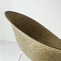 "Curved bowl chair in earthy brown with a textured finish and white metal legs."