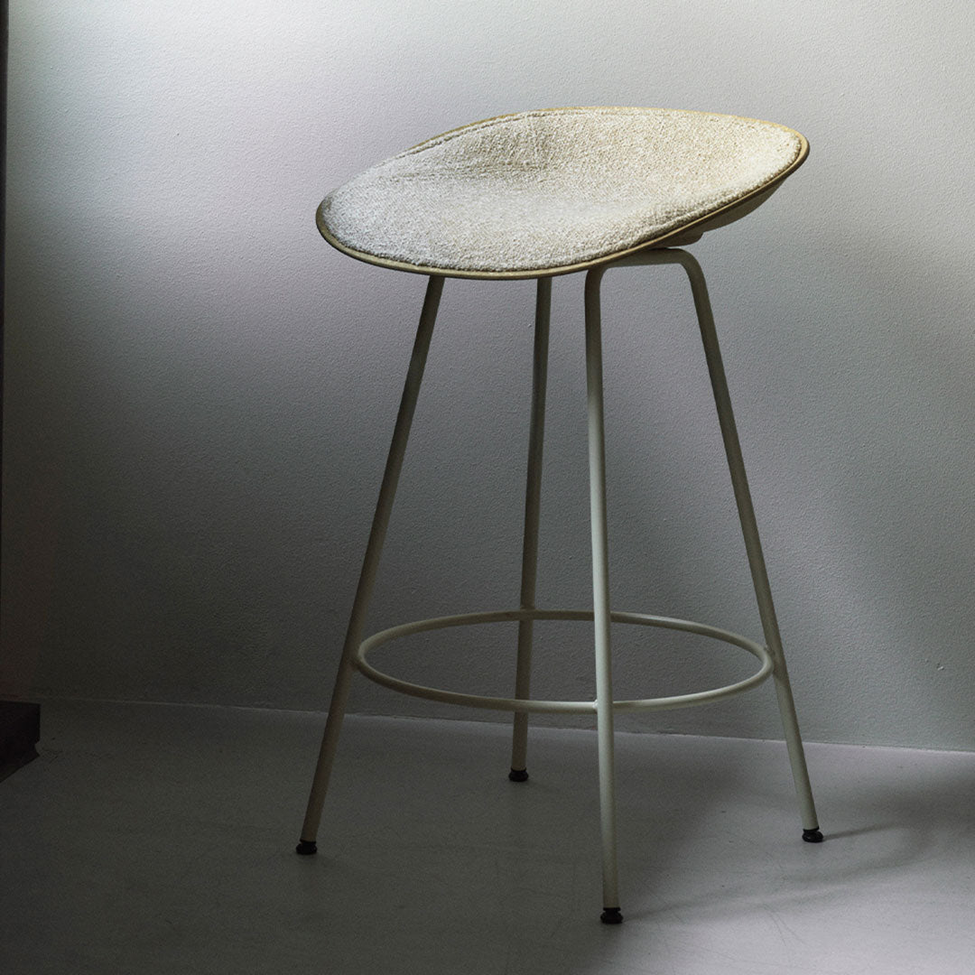 Modern white bar stool with a textured seat and sleek metal legs, perfect for contemporary decor.