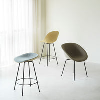 Set of three modern bar stools in soft blue, warm beige, and deep olive green, with sleek black metal legs.