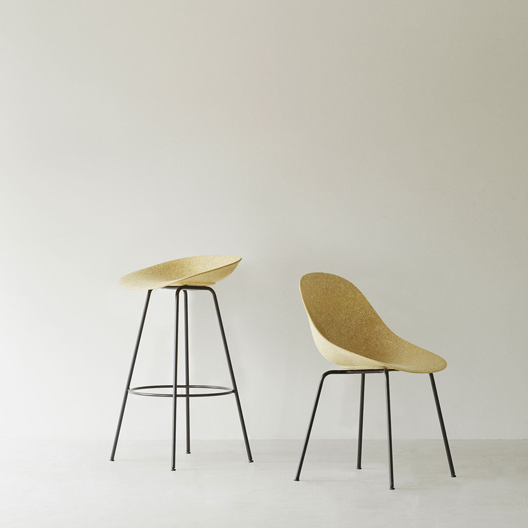 Two modern bar stools with a soft beige finish and sleek black metal legs, minimalistic design against a light background.