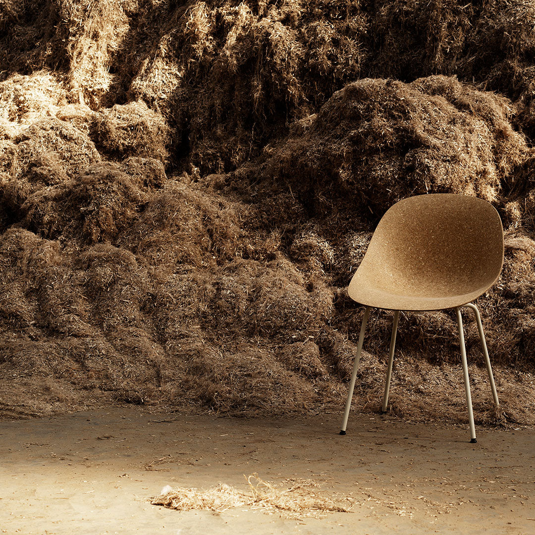Brown ergonomic chair against a textured, earthy background of natural fibers and soft hues. Perfect for modern decor.
