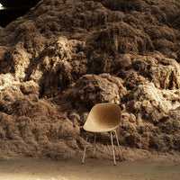 Modern cream chair with sleek silver legs against a backdrop of textured beige and earthy brown tones.