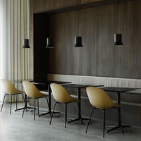 Modern black pendant lights above sleek black tables and stylish beige chairs in a minimalist interior.