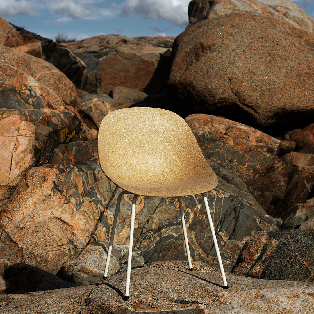 Beige speckled chair against a backdrop of rocky earth tones and textures. Chic and modern design.