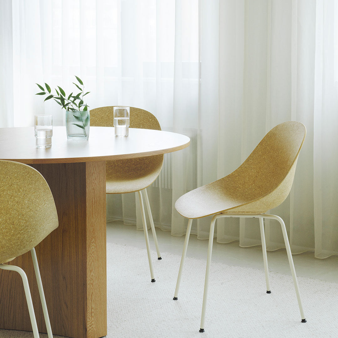 Light beige chairs with a textured finish around a wooden table, complemented by soft, neutral curtains.