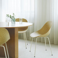 Light beige chairs with a textured finish around a wooden table, complemented by soft, neutral curtains.