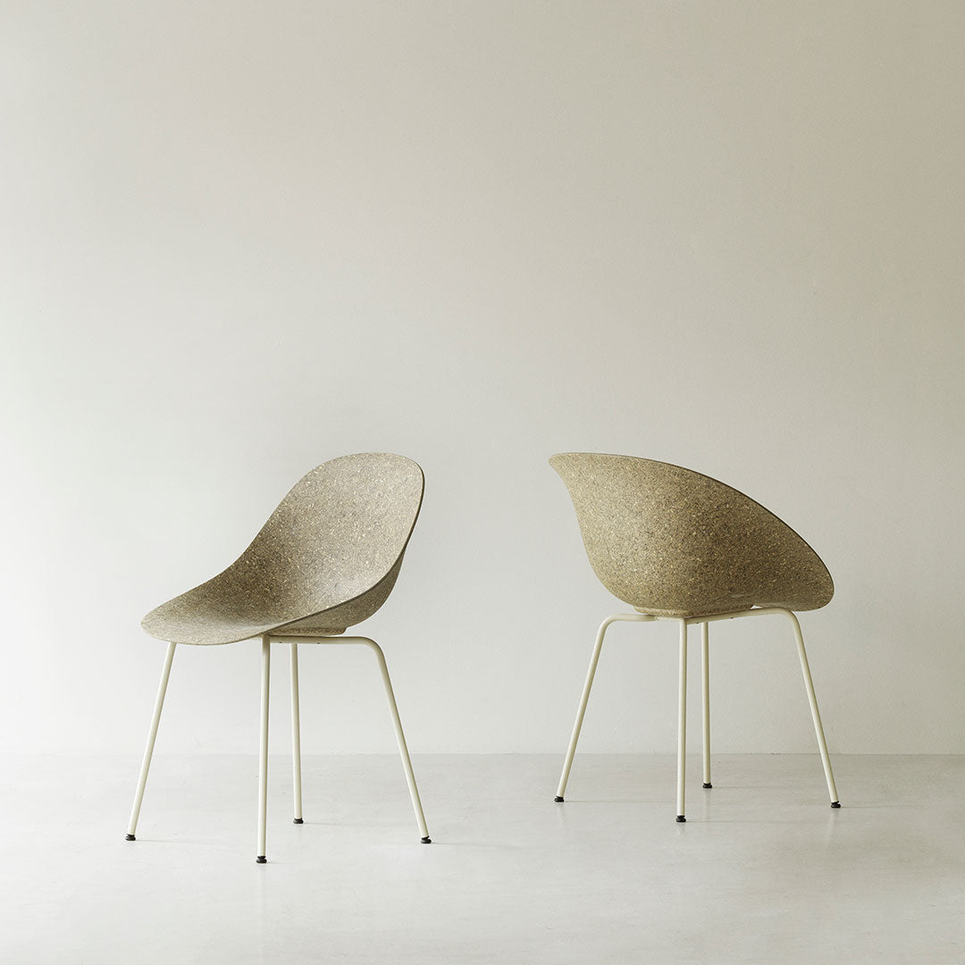 Beige textured chair with smooth curves and slender white metal legs against a soft neutral background.