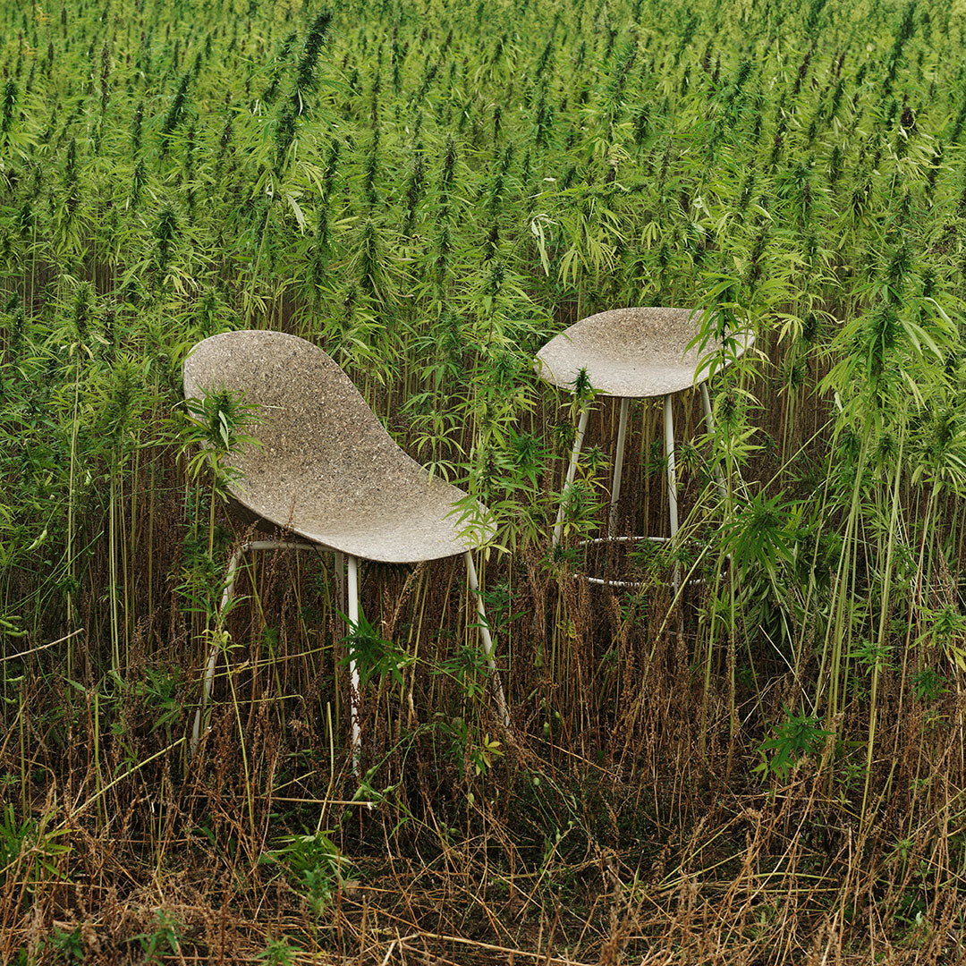 Gray patterned chairs blend with vibrant green foliage, showcasing a natural, organic aesthetic in a field setting.