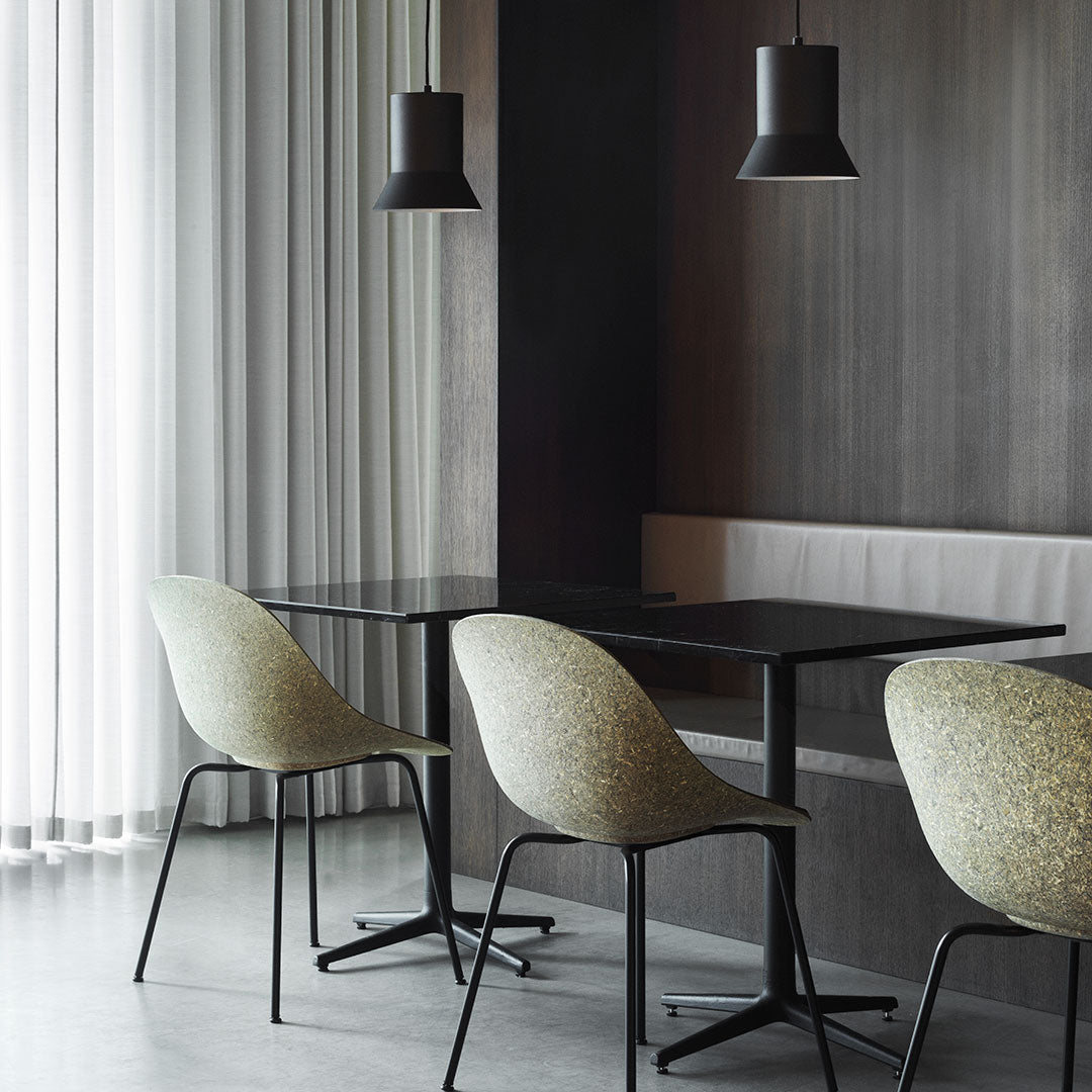 "Light green patterned chairs with black metal legs against a dark wood wall and soft gray flooring."