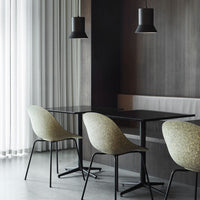 "Light green patterned chairs with black metal legs against a dark wood wall and soft gray flooring."