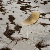 Light beige chair with a textured surface, set against a sandy background with dark, wavy patterns.